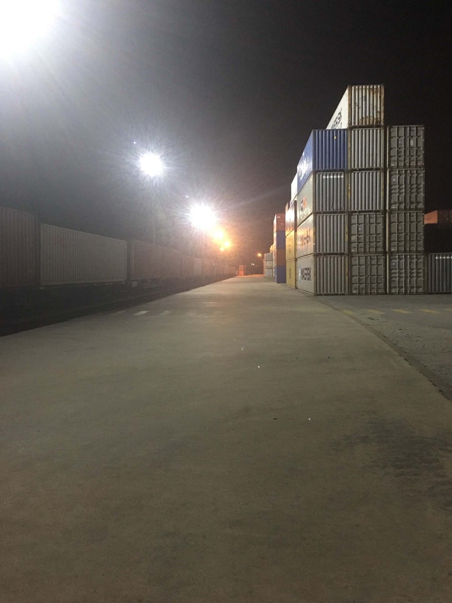 Container terminal at night lit by high power LED flood lights mounted on poles